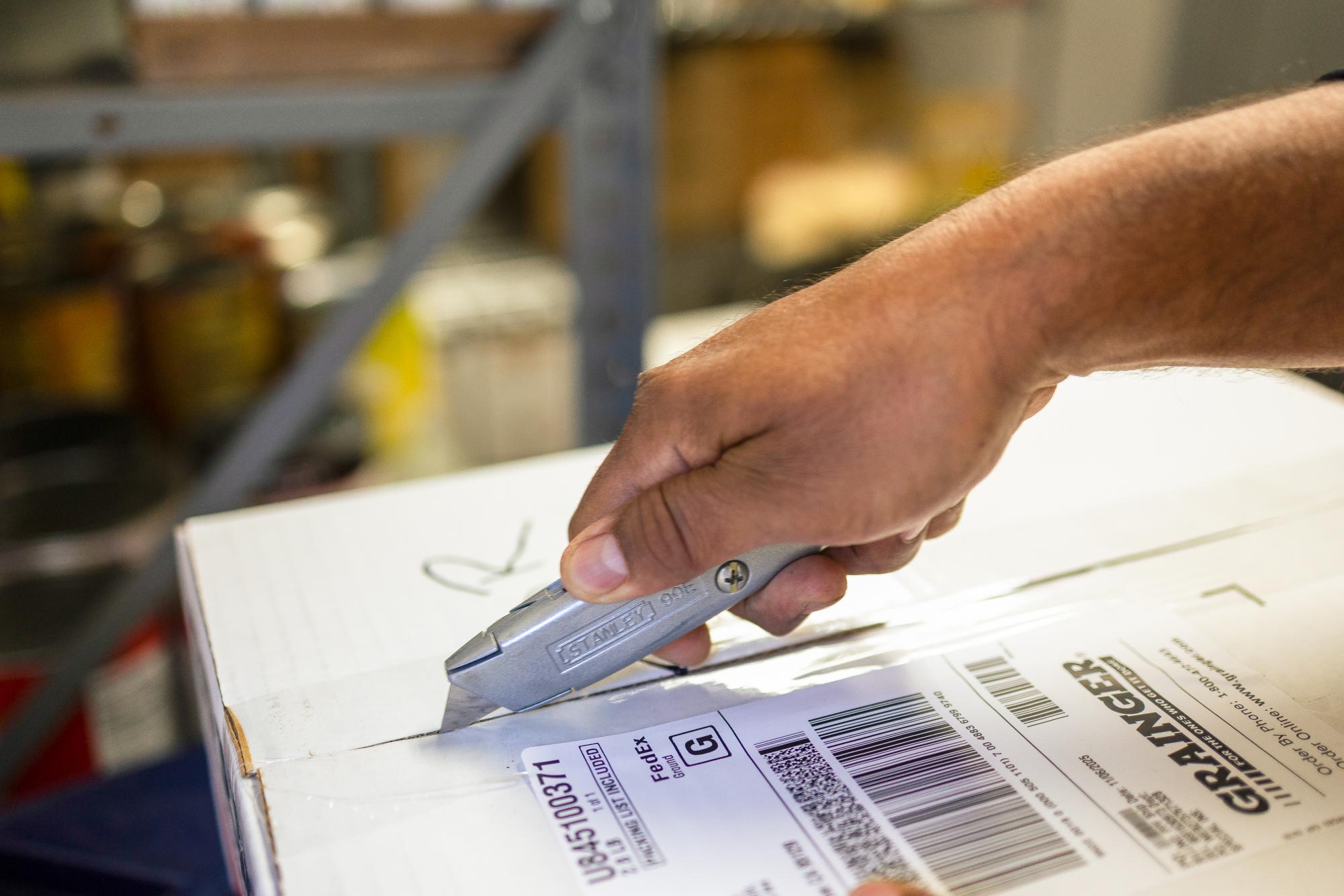 Shipping and Receiving Associate Raul Rios slices through tape on a delivery he received. Rios has worked at Harker for 25 years. 