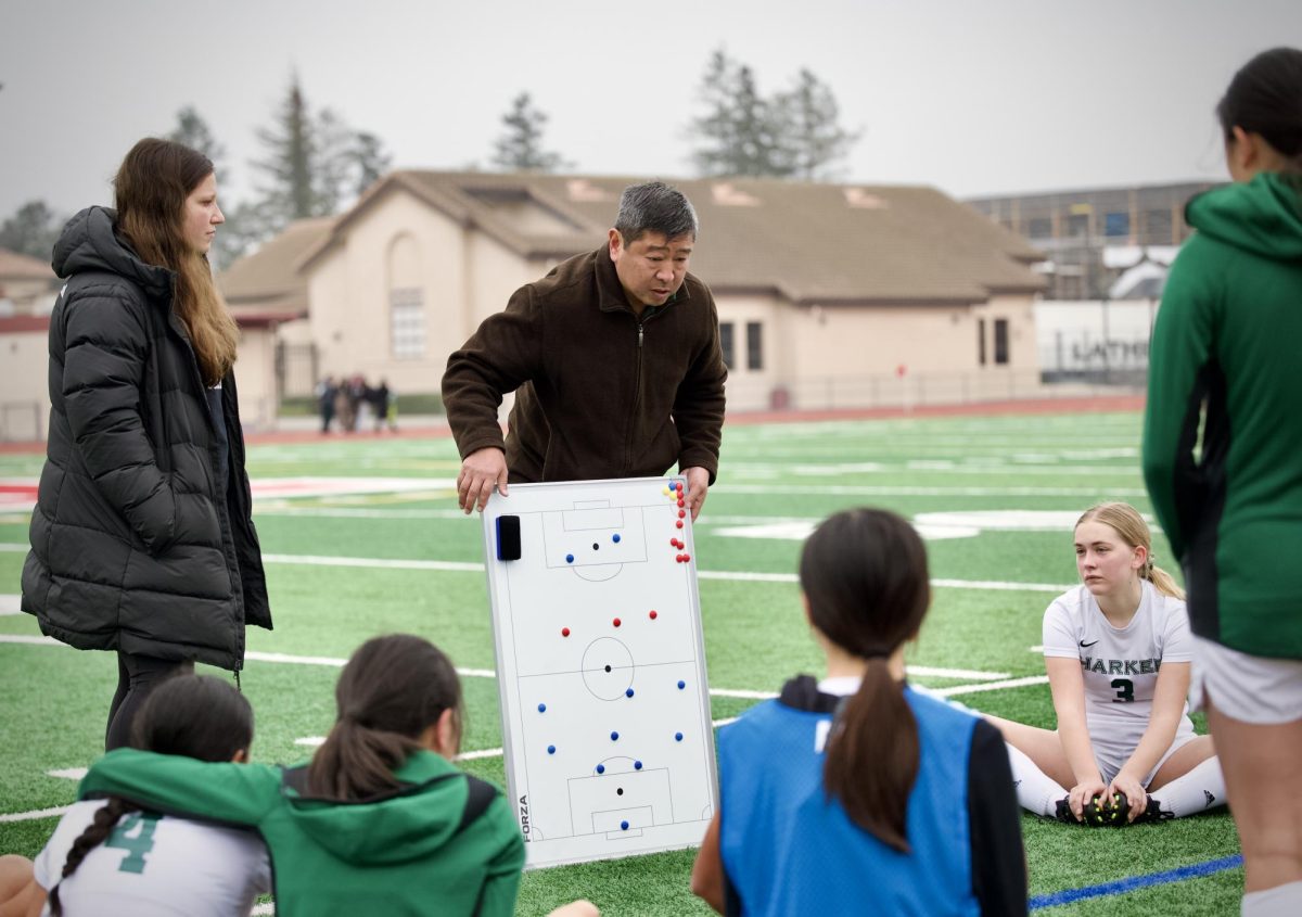 Assistant coach Jorge Chen draws out a play for the varsity girls soccer team. The team employed a variety of plays throughout the game, in particular a strategy where midfielder Eva Cheng (12) drives past two defenders and slips the ball to the wing players.
