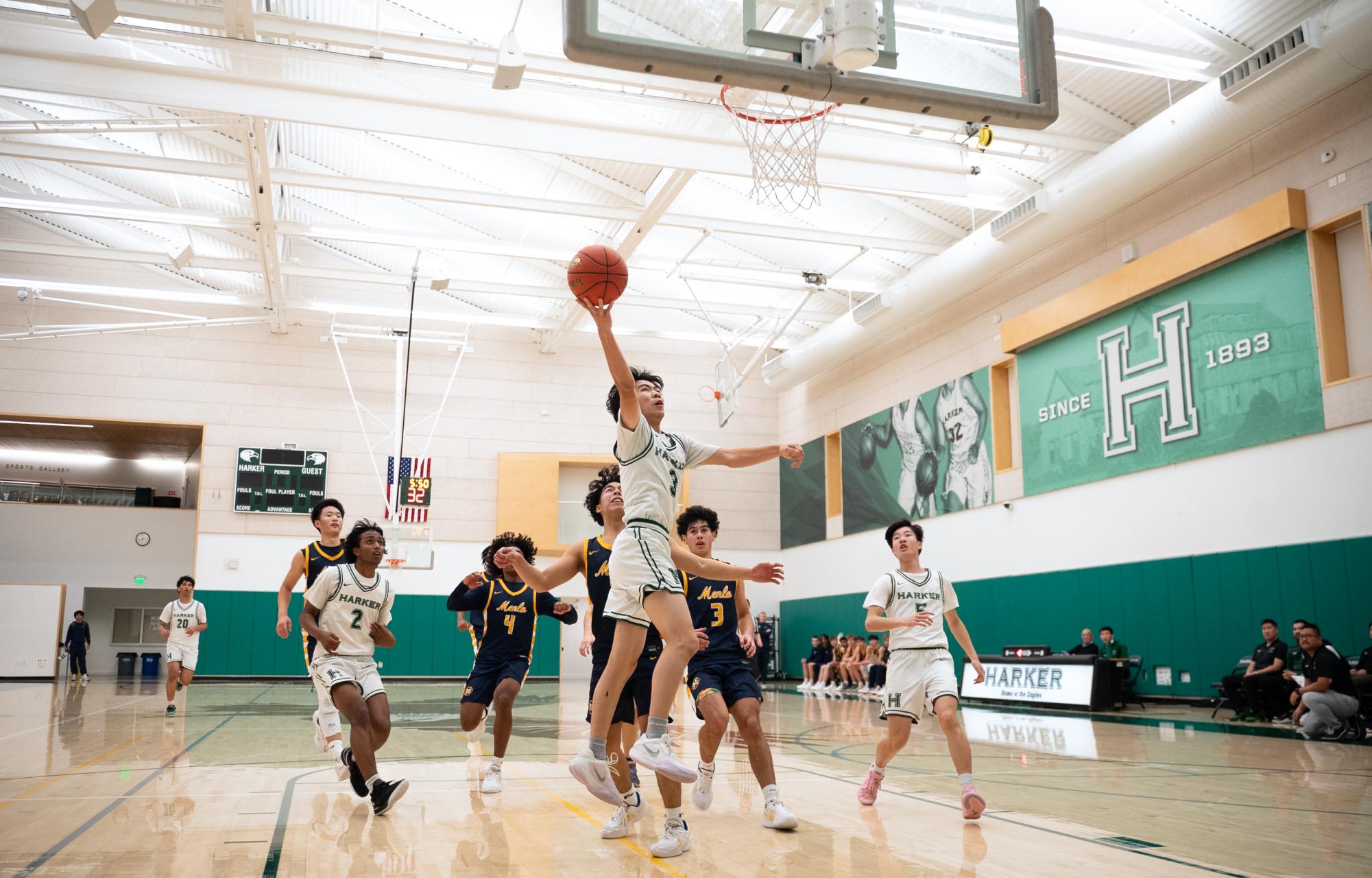 Point guard Caden Ruan (12) converts a layup on a fast break. Due to Menlo's stifling defense when the Eagles got into more organized sets, they had to take advantage of chaotic plays like fast breaks to score points.