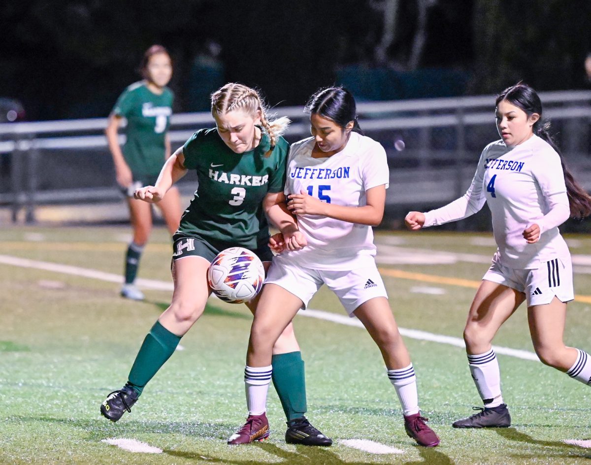 Forward Natalie Barth (12) shields the ball from two Jefferson defenders during Harker’s match on Davis Field. Harker remained composed under pressure, allowing the team to sustain its offensive play.