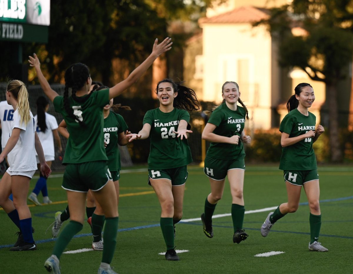 Varsity girls soccer midfielder MacEnzie Blue (12) runs to celebrate forward Aanya Sharma (12)'s goal in their senior night game. In many of the team's league games, they secured double-digit victories.