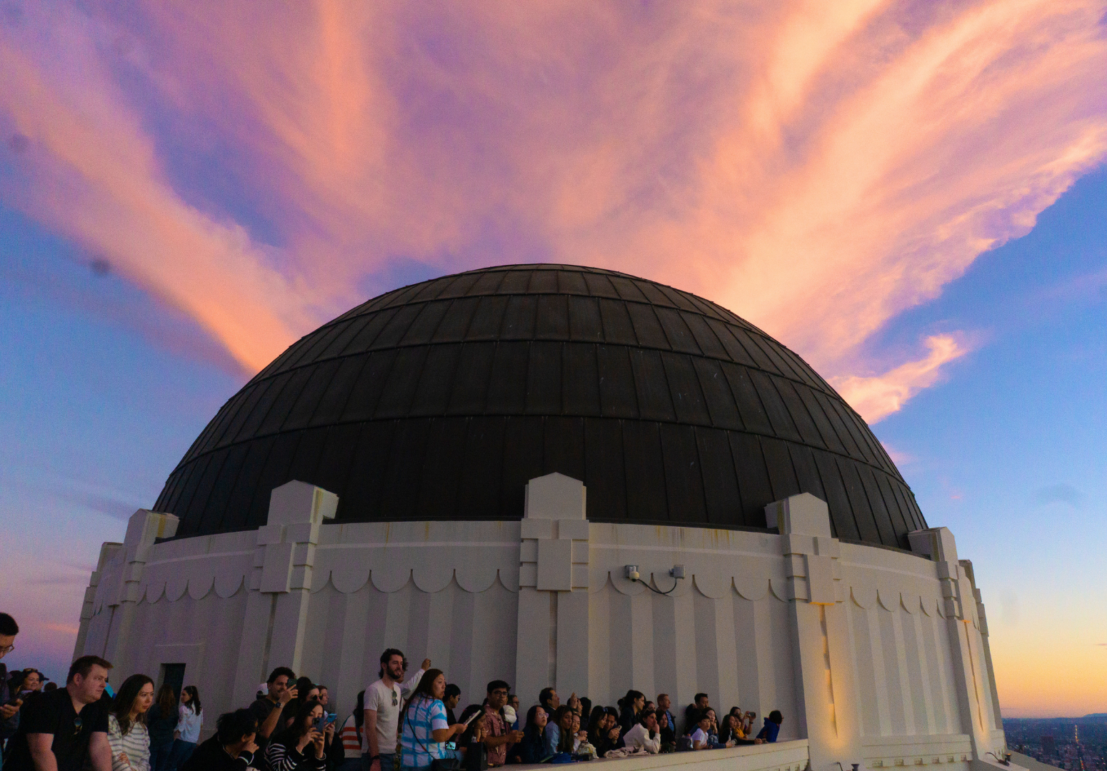 The setting sun illuminates clouds above the Griffith Observatory, crowing the dome with fiery wisps.