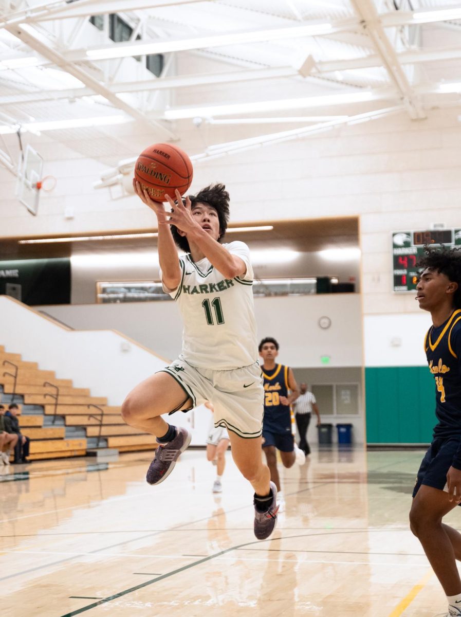 Varsity boys basketball guard Robinson Xiang (12) rises up to finish a layup. The team remained resilient this season despite multiple injuries and game losses.