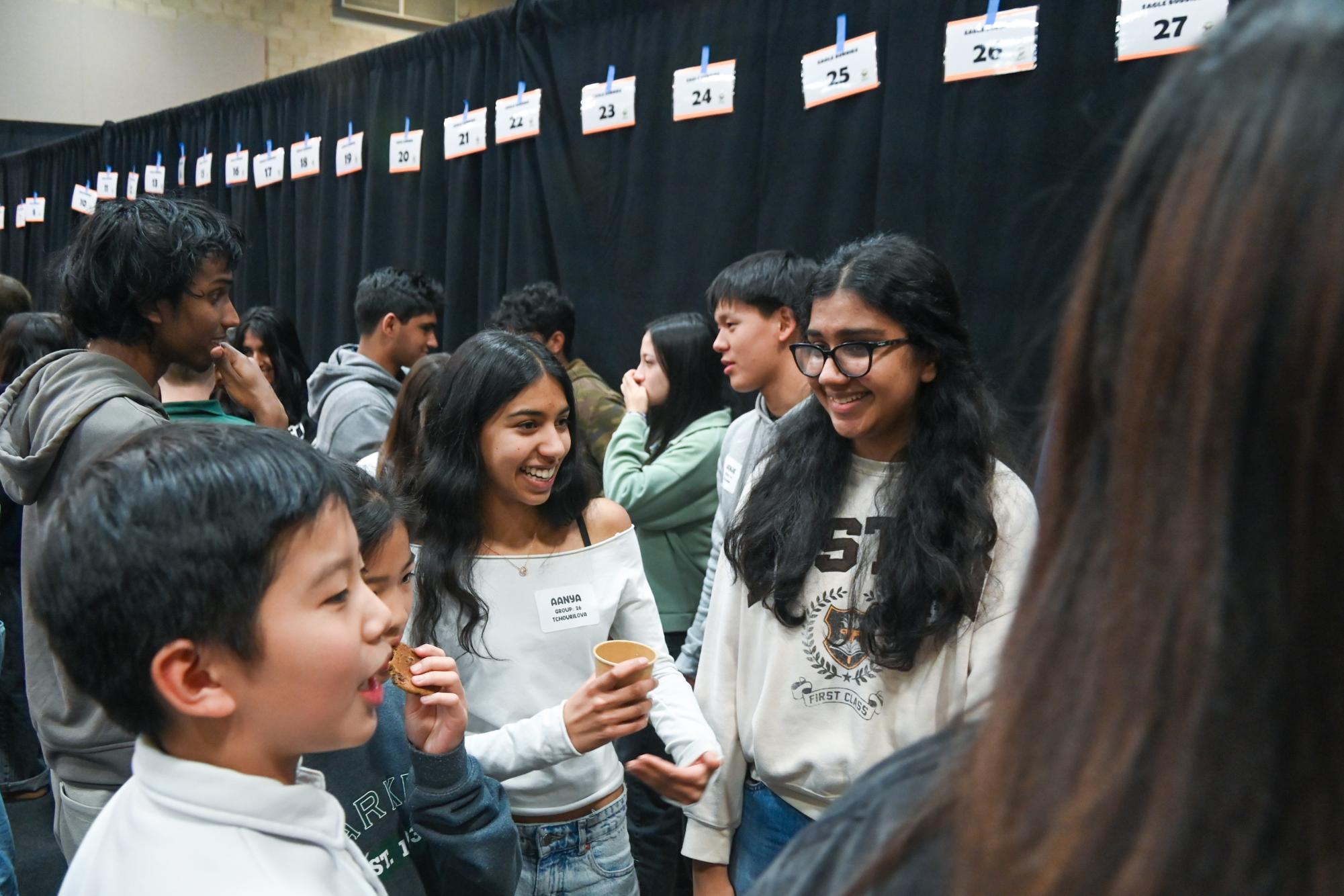 Seniors Aanya Shah and Amishi Gupta laugh with their Eagle Buddies after watching the fifth grade show. After the performance, the fifth graders joined their senior buddies in the gym to celebrate.