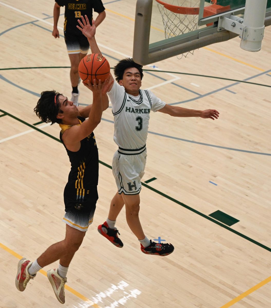 Varsity boys basketball guard Caden Ruan (12) blocks a Del Mar player in their season opener game. The team ultimately prevailed 63-53, setting a positive tone for the rest of their season.
