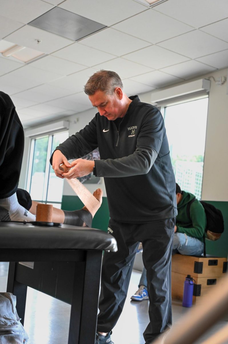 Athletic trainer Wes Howard wraps a foot  using bandages. Bandages for injuries help reduce swelling and relieve pressure for an athlete.
