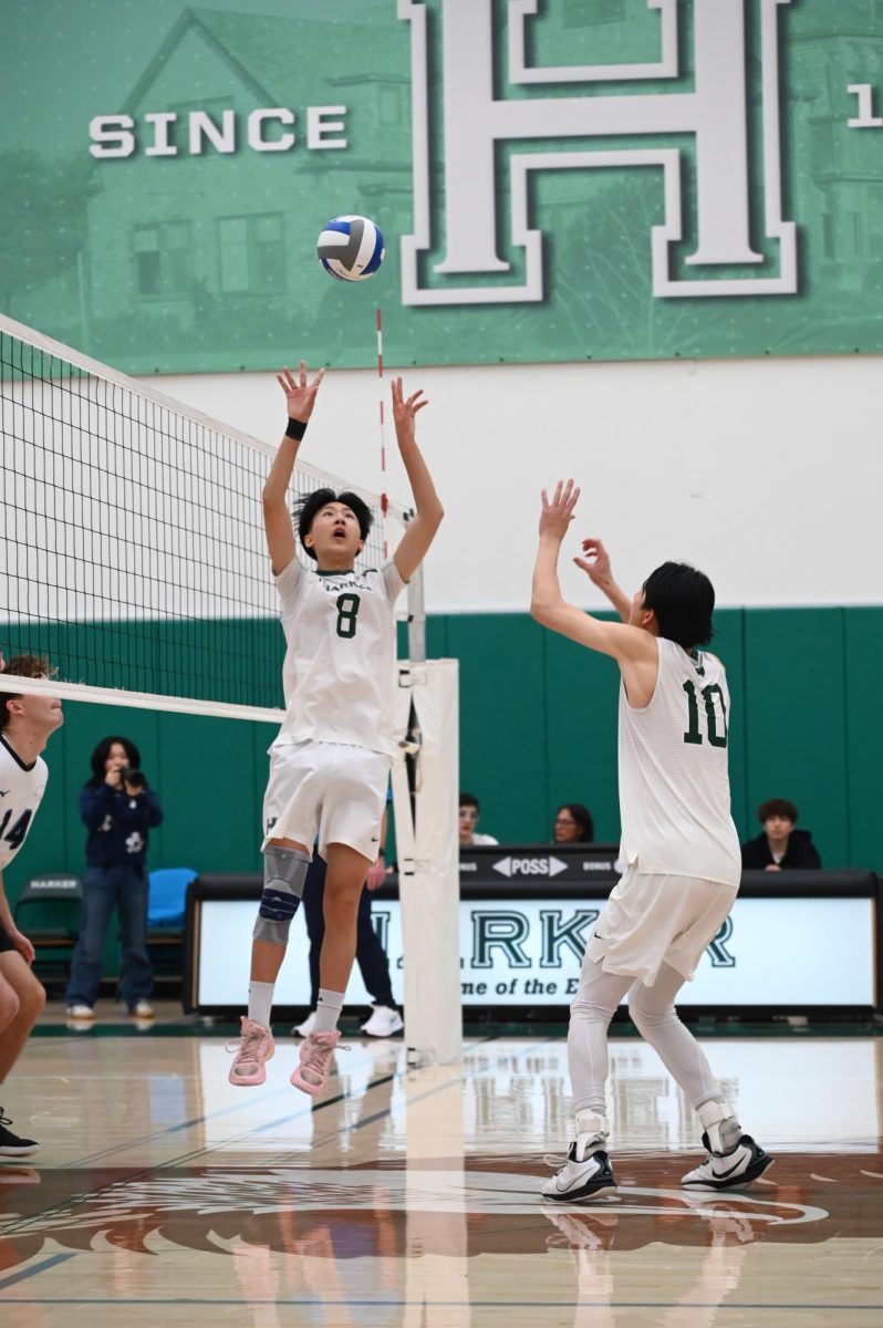 Setter Brandon Labio (11) sets the ball high for co-captain and middle Kairui Sun (12). Brandon contributed multiple successful serves during the game to help Harker win the third and fourth sets.
