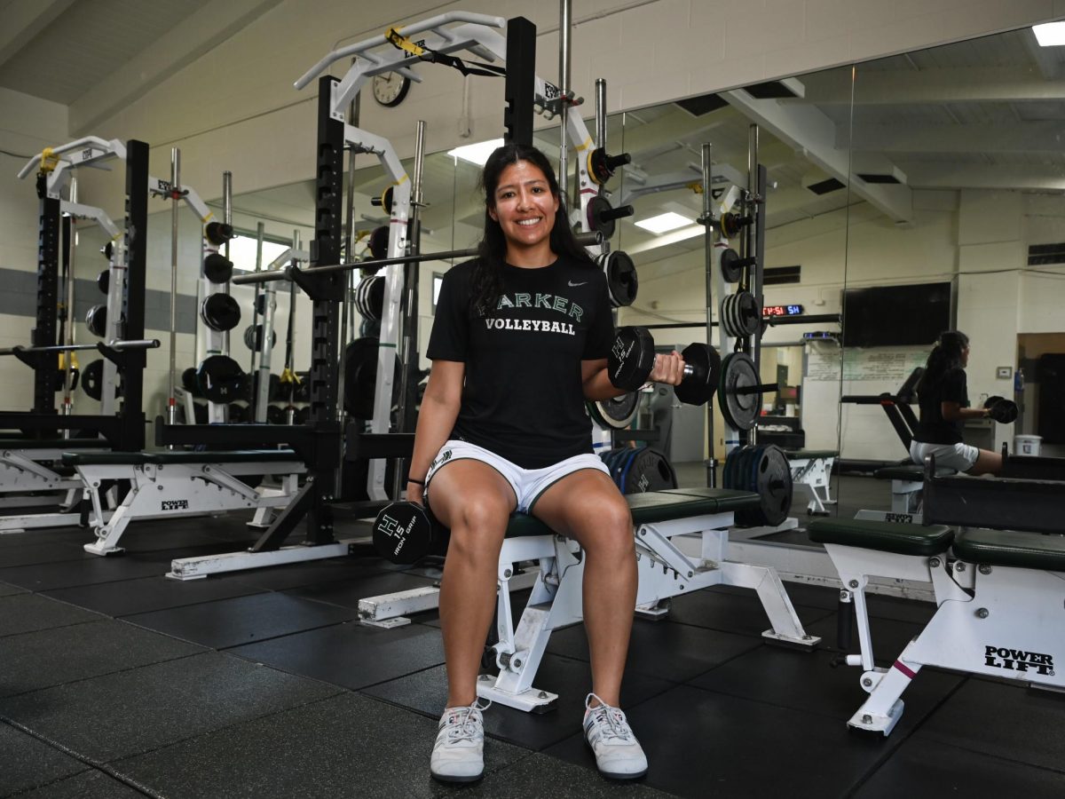 Strength and conditioning coordinator Marlen Castaneda smiles as she holds up a weighted dumbell. Castaneda helps train all athletes in addition to tracking PE credits for all students.
