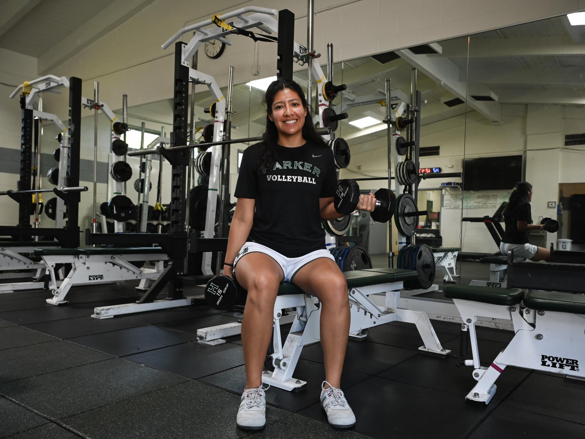 Strength and conditioning coordinator Marlen Castaneda smiles as she holds up a weighted dumbell. Castaneda helps train all athletes in addition to tracking PE credits for all students.
