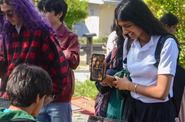Junior Riya Samuel shows a picture of her younger self to an HSLT representative. Students were required to provide a physical or digital photo of the outfit they were recreating in order to gain spirit points.