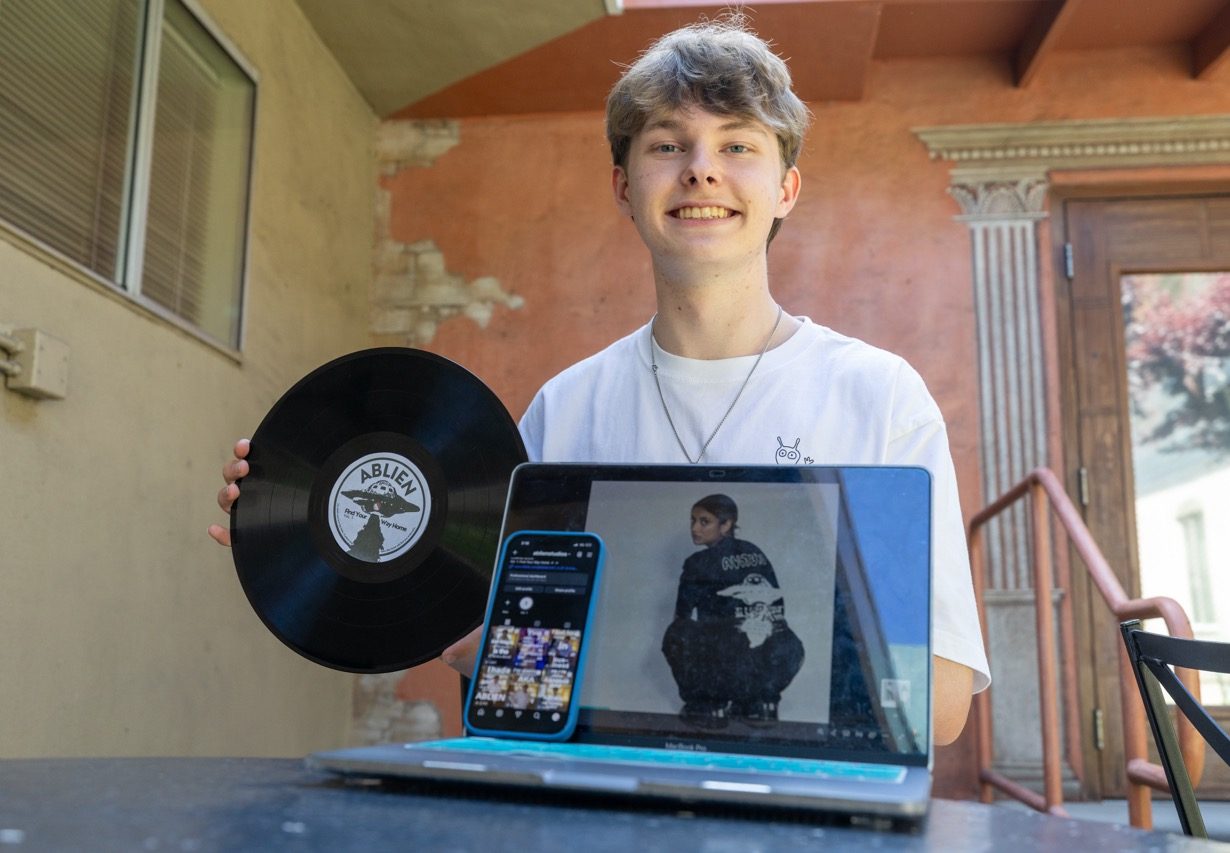 Junior Stellan Lindh displays a custom vinyl record for his clothing company, Ablien, alongside a professional photoshoot on his laptop and social media advertising on his phone. For students with side hustles, building a multimedia presence can be a great way to connect with consumers and expand their brand.