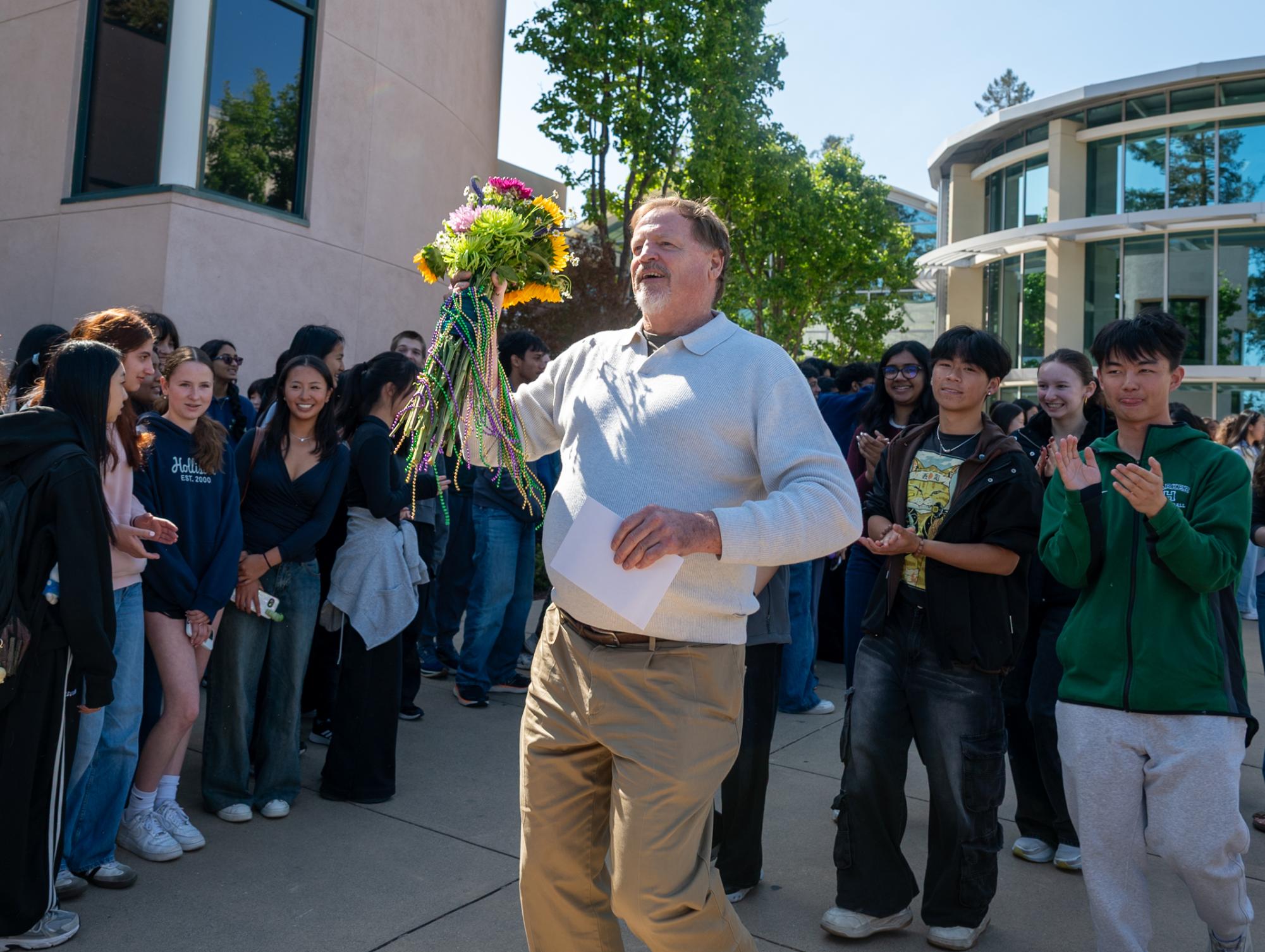 Dean of Students Kevin Williamson holds a bouquet of flowers. Students and faculty marched in a celebratory parade to honor Williamson, who is retiring after 26 years at Harker, on Tuesday.