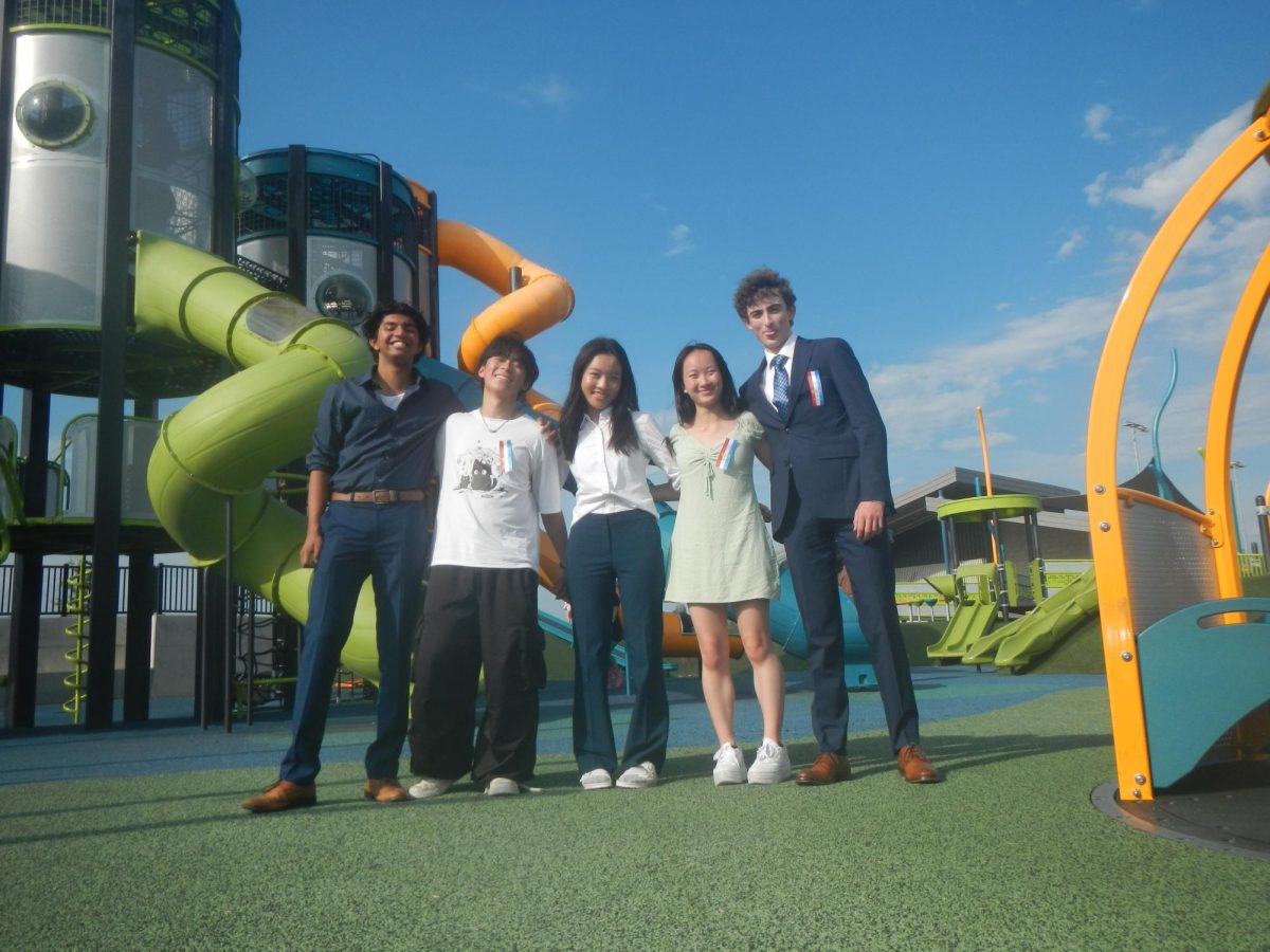 The speech and debate team poses in front of a playground. Some of Joy's favorite memories come from a competition with them in Des Moines.