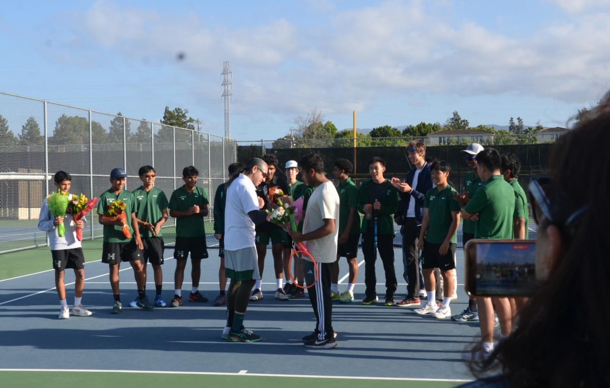 Varsity boy tennis coach John Fruterro hands out flowers to the seniors. The team celebrated their seniors in a ceremony after the matches.