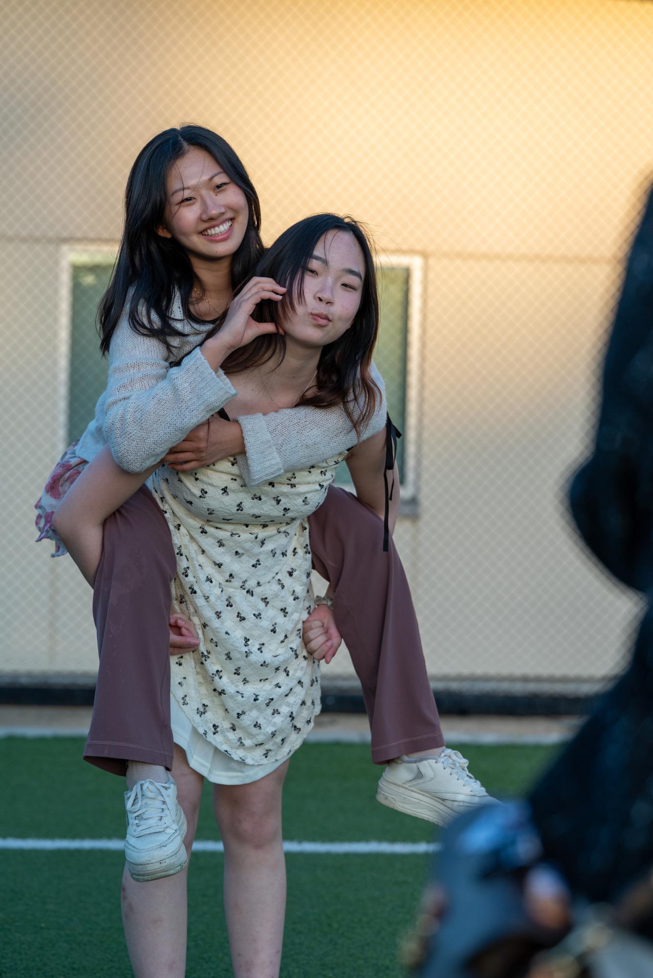 Juniors Isabelle Niu and Cynthia Wang take photos together on Davis Field. Students gathered around campus with their friends to take pictures after the ceremony.