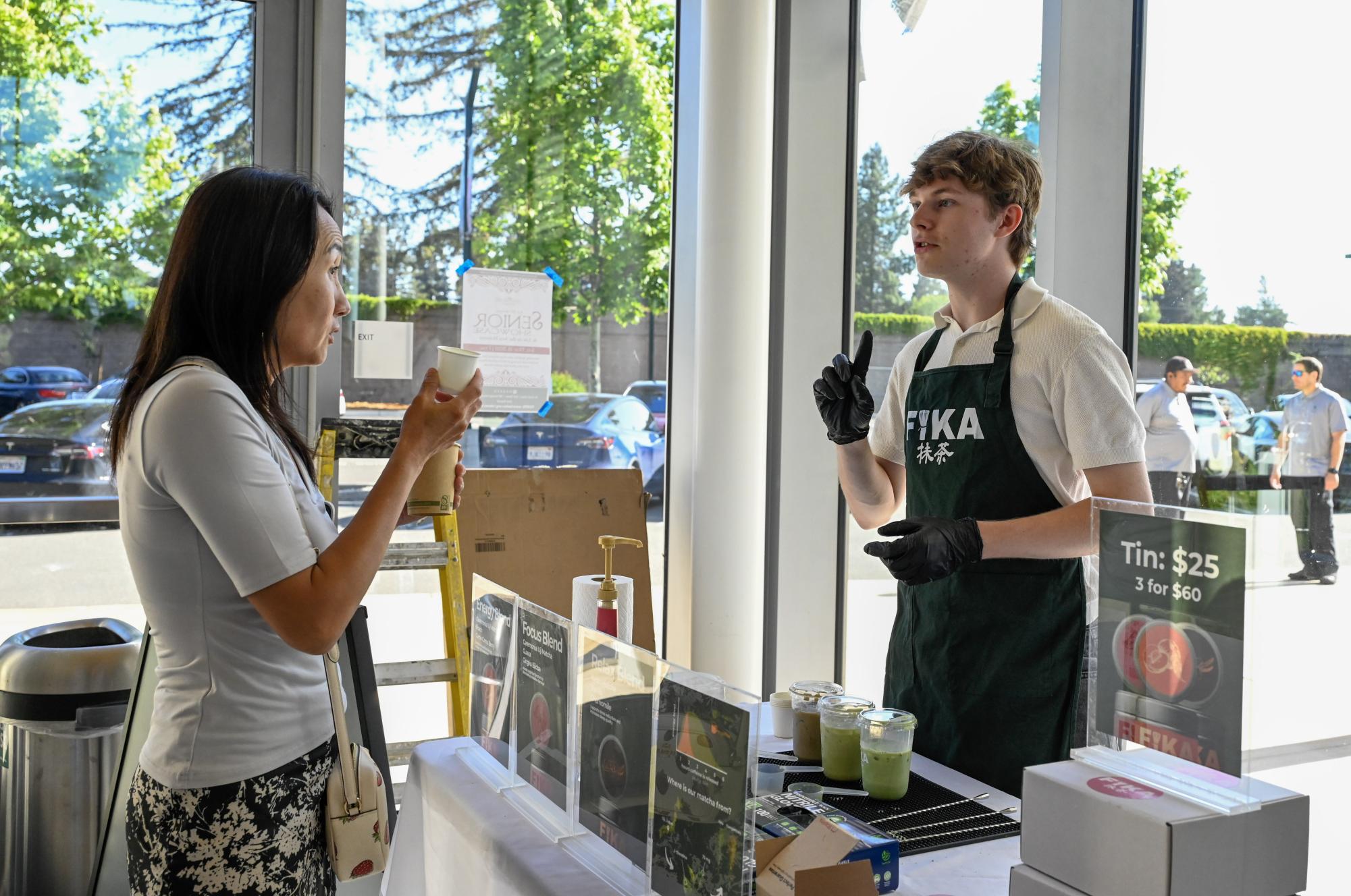 FIKA Matcha founder Stellan Lindh (11) explains his product to a parent. FIKA Matcha comes in three blends: energy, focus and relax and is sugar-free beverage.